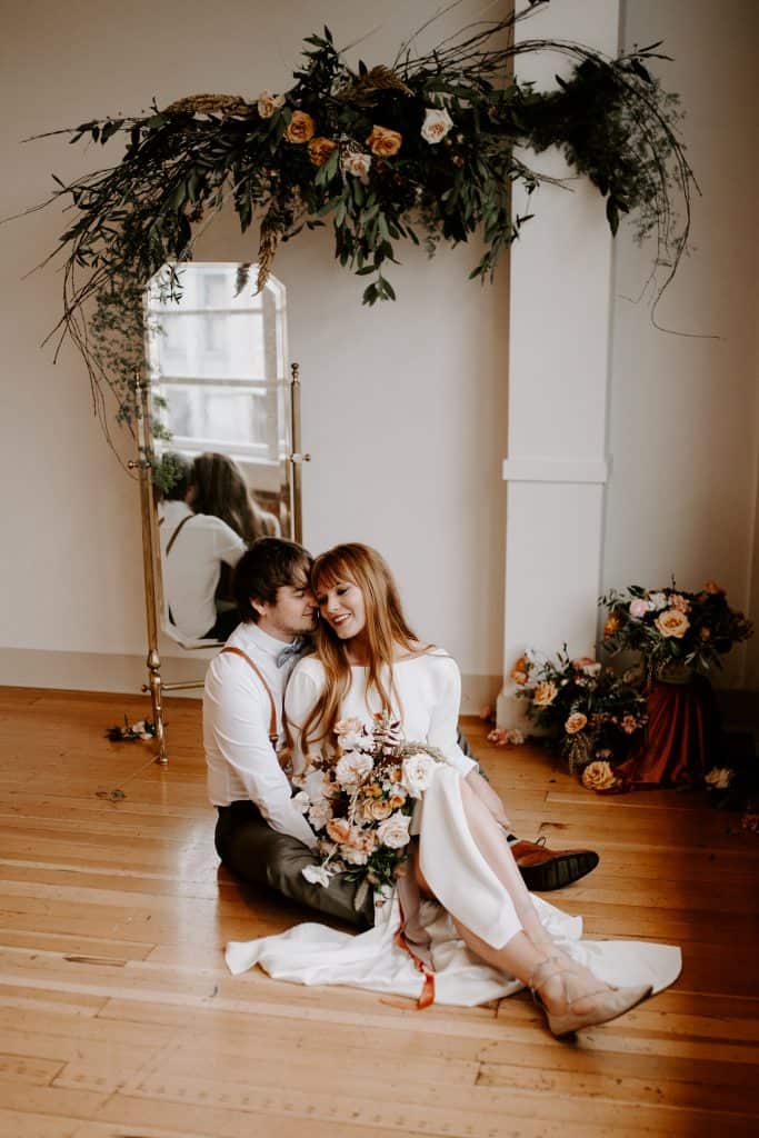 bride and groom sit on the floor snuggled together after adventure elopement ceremony