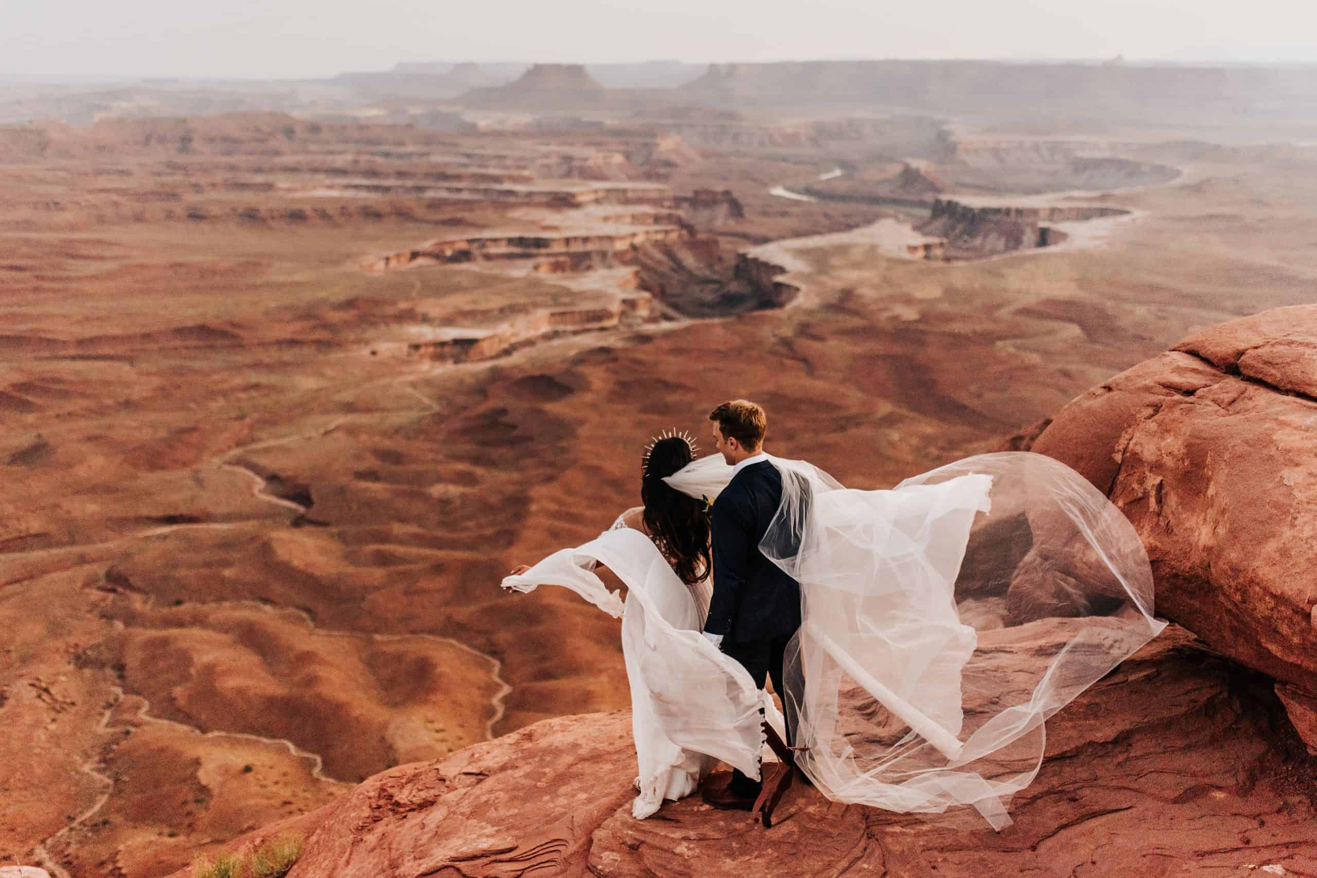 newlywed couple over look a canyon while doing classic Titanic pose