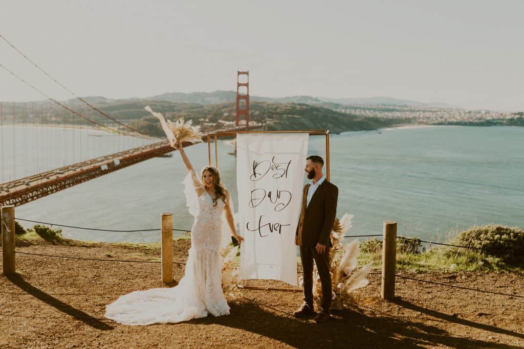 newlyweds celebrate their elopement in front of their Best Day Ever ceremony panel at sunrise