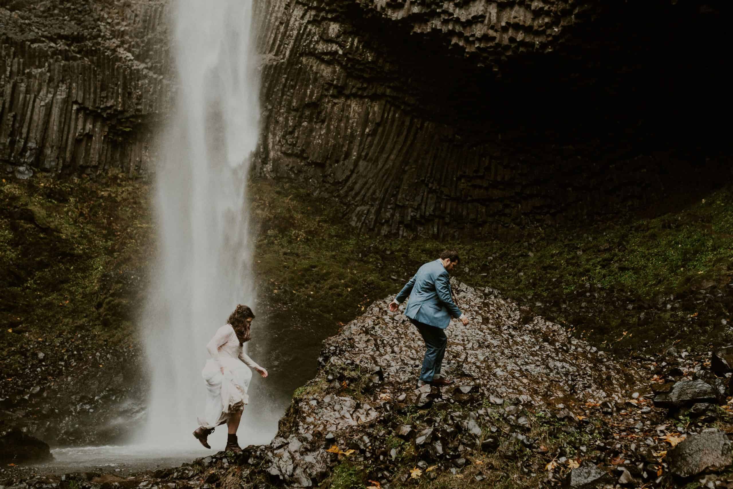 bride follows groom while walking towards waterfall photo by Katie Berg Photo