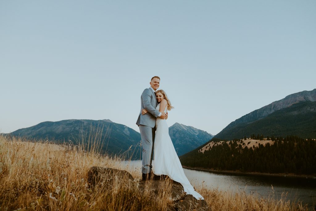 bride and groom standing in front of wallowa lake
