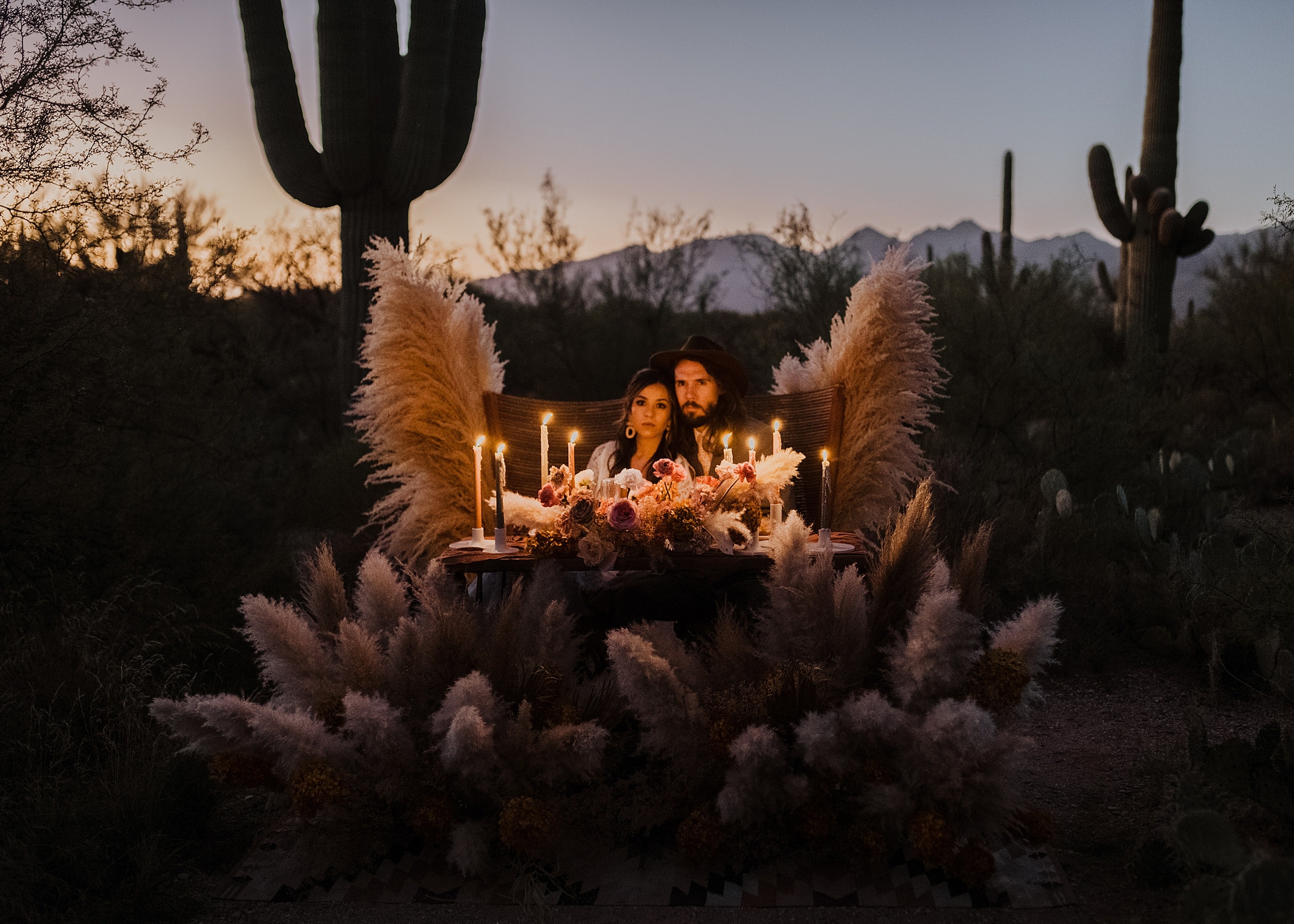 couple sitting in arrangement with candle light in evening at saguaro national park 