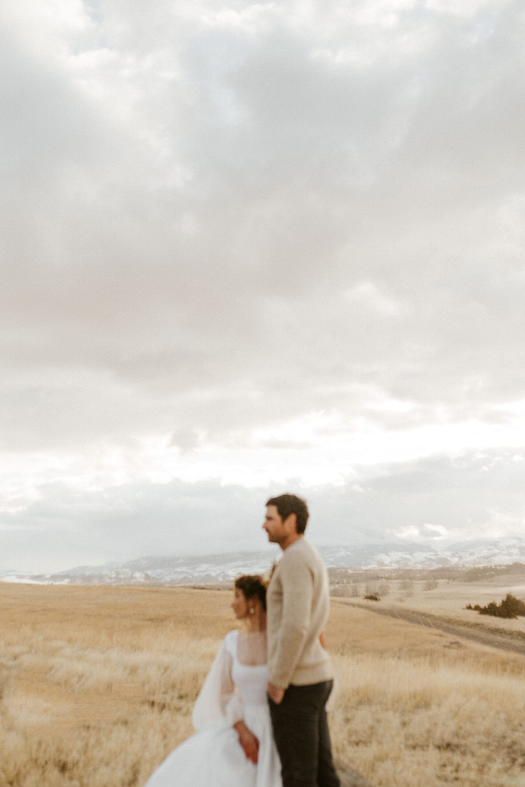 couple standing on plains in front of hills 