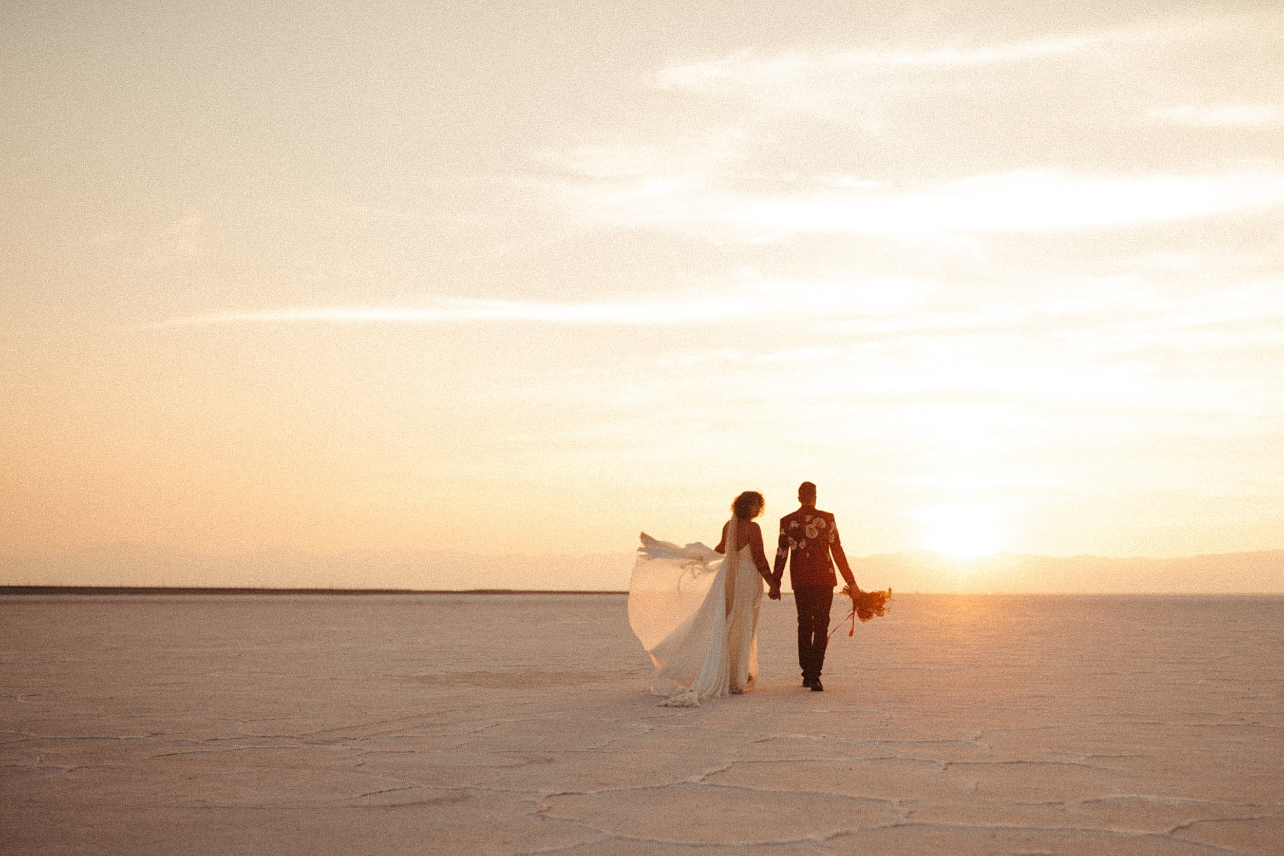 bride and groom walking together bonneville salt flats landscape
