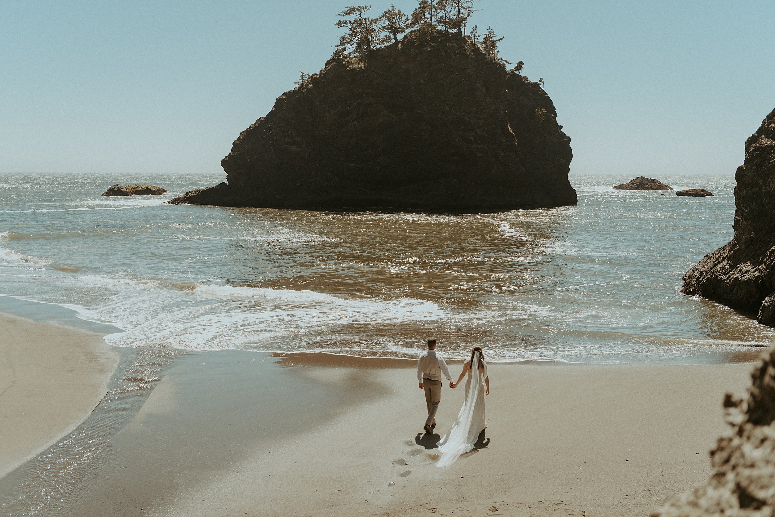 bride and groom walking together on beach 