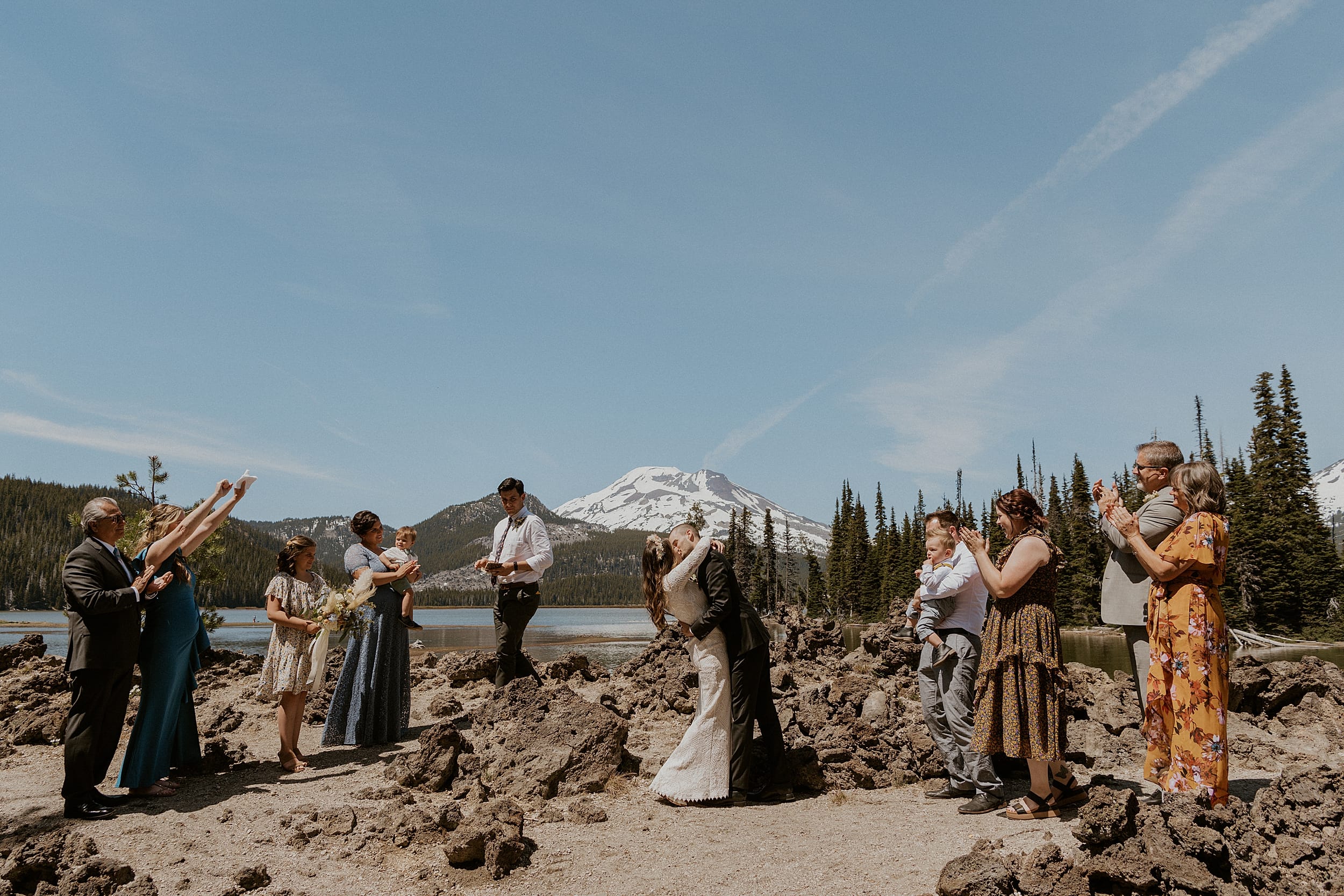 bride and groom kissing surrounded by wedding part mountain forest landscape