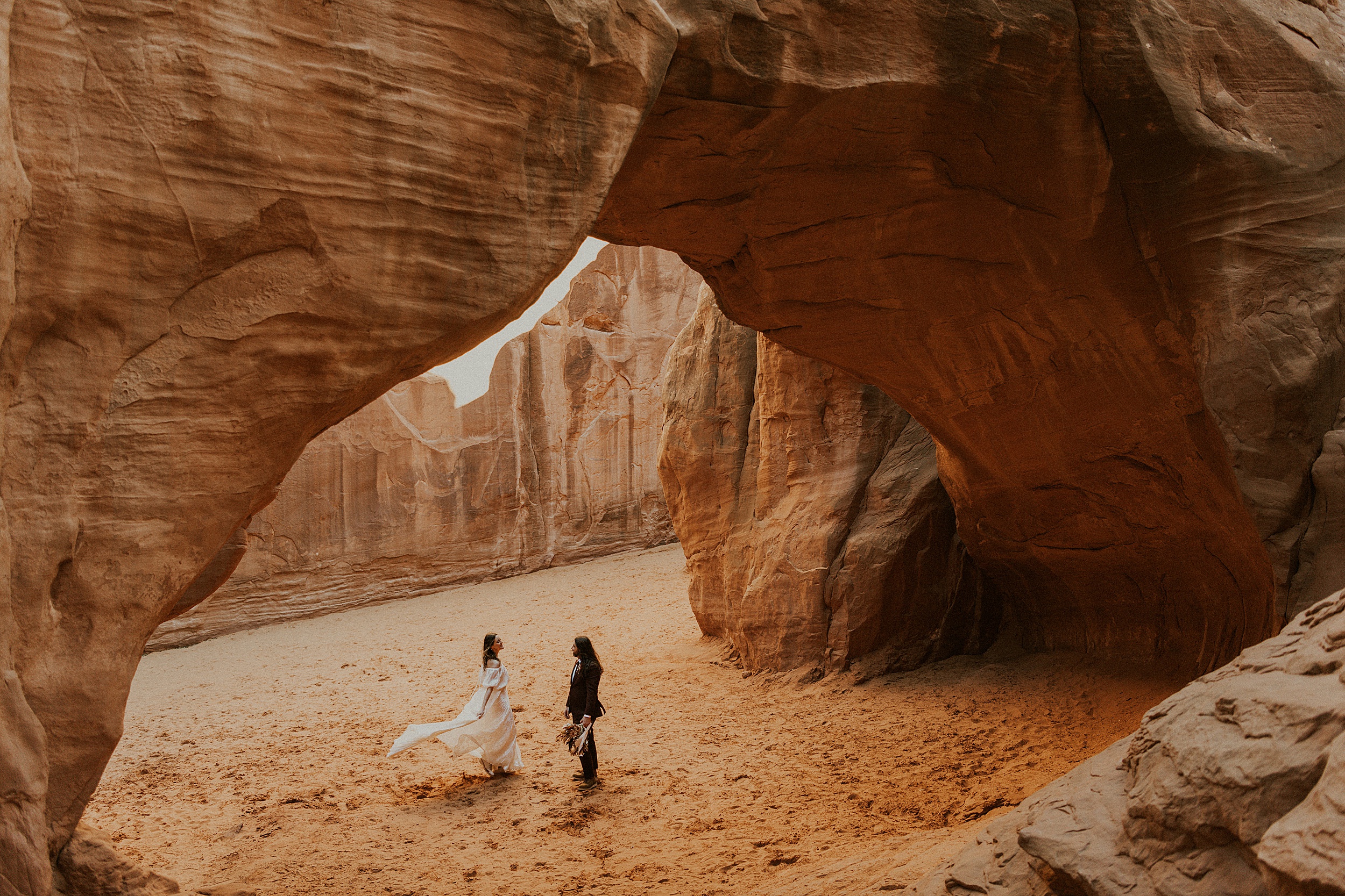 couple walking through arches national park