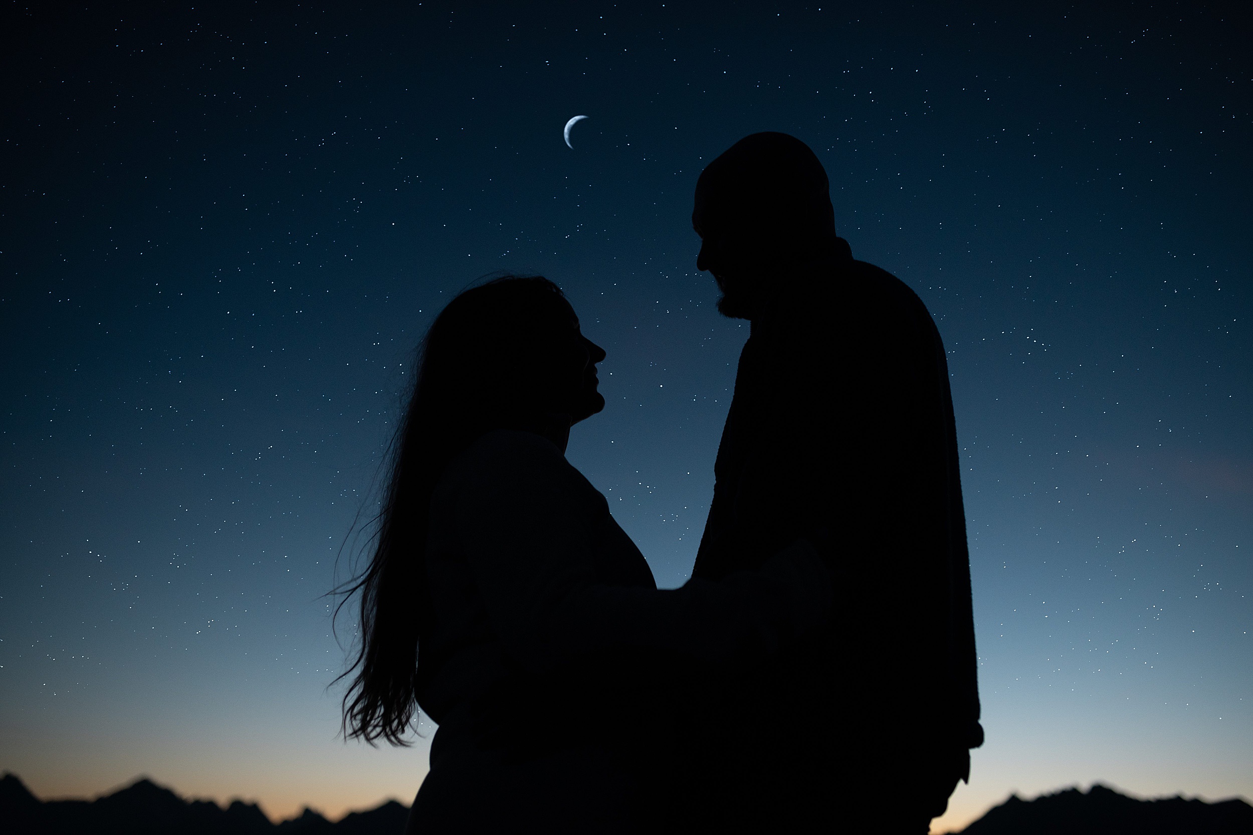 couple standing under crescent moon